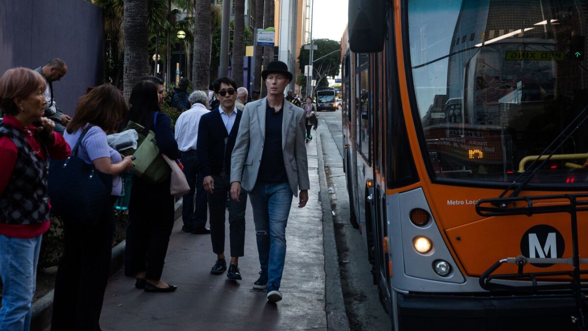 People wait to board a bus in downtown Los Angeles. One proposal to speed up buses is all-door boarding.