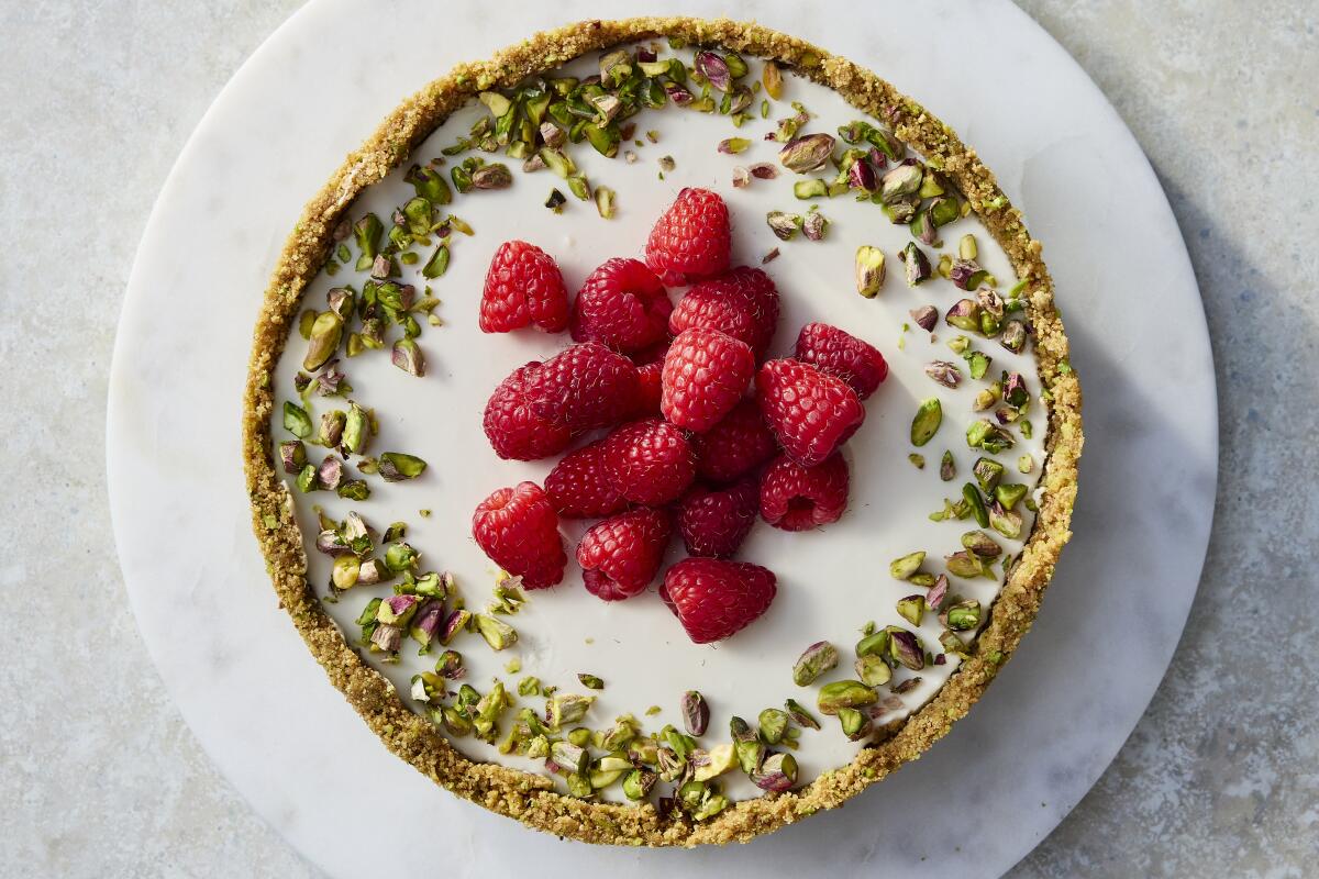 Bird's-eye view of no-bake cheesecake with chopped pistachios and raspberries on top.