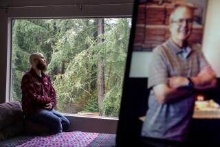 Nathan Lambrecht is photographed next to a picture of his father, Doug Lambrecht, at his apartment in Woodinville, Wash., Monday, March 21, 2022. The 71-year-old retired physician was among the first of the nearly 1 million Americans to die from COVID-19. "I'm afraid that as the numbers get bigger, people are going to care less and less," Nathan said. "I just hope people who didn't know them and didn't have the same sort of loss in their lives due to COVID, I just hope that they don't forget and they remember to care." (AP Photo/David Goldman)