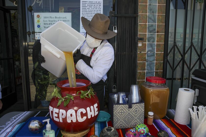 Los Angeles, CA - June 12: Alexander Lopez, 39, gets ready to serve Tepache drink. Oaxacan migrants make traditional meals and give them out for free on side-walk in front of flower shop Yeaj Yalhalhj on Saturday, June 12, 2021 in Los Angeles, CA. (Irfan Khan / Los Angeles Times)