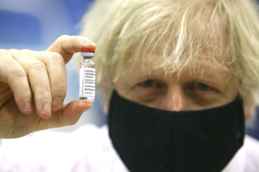 FILE - In this Wednesday, Feb. 17, 2021 file photo, Britain's Prime Minister Boris Johnson holds a vial of the Oxford/Astra Zeneca Covid-19 vaccine at a vaccination centre in Cwmbran, south Wales. The British government says it aims to give every adult in the country a first dose of coronavirus vaccine by July 31, a month earlier than its previous target. In addition, the goal is for everyone over 50 or with an underlying health condition to get a shot by April 15, rather than the previous target of May 1. (Geoff Caddick/Pool via AP, File)