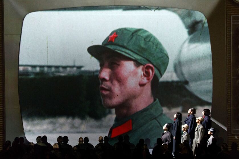 Actors as Chinese communists perform with the LA Philharmonic as a large projection screen shows TV footage from China of Air Force One arriving at the airport in a performance of "Nixon In China" at the Walt Disney Concert Hall on Friday, March 3, 2017 in Los Angeles, Calif. (Patrick T. Fallon/ For The Los Angeles Times)