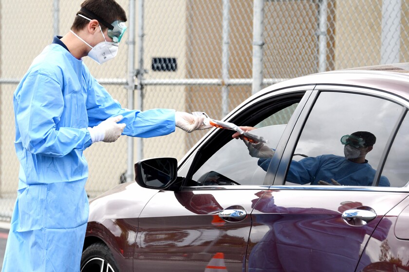 Jeremy Rocha hands out a coronavirus test kit at a drive-thru testing site