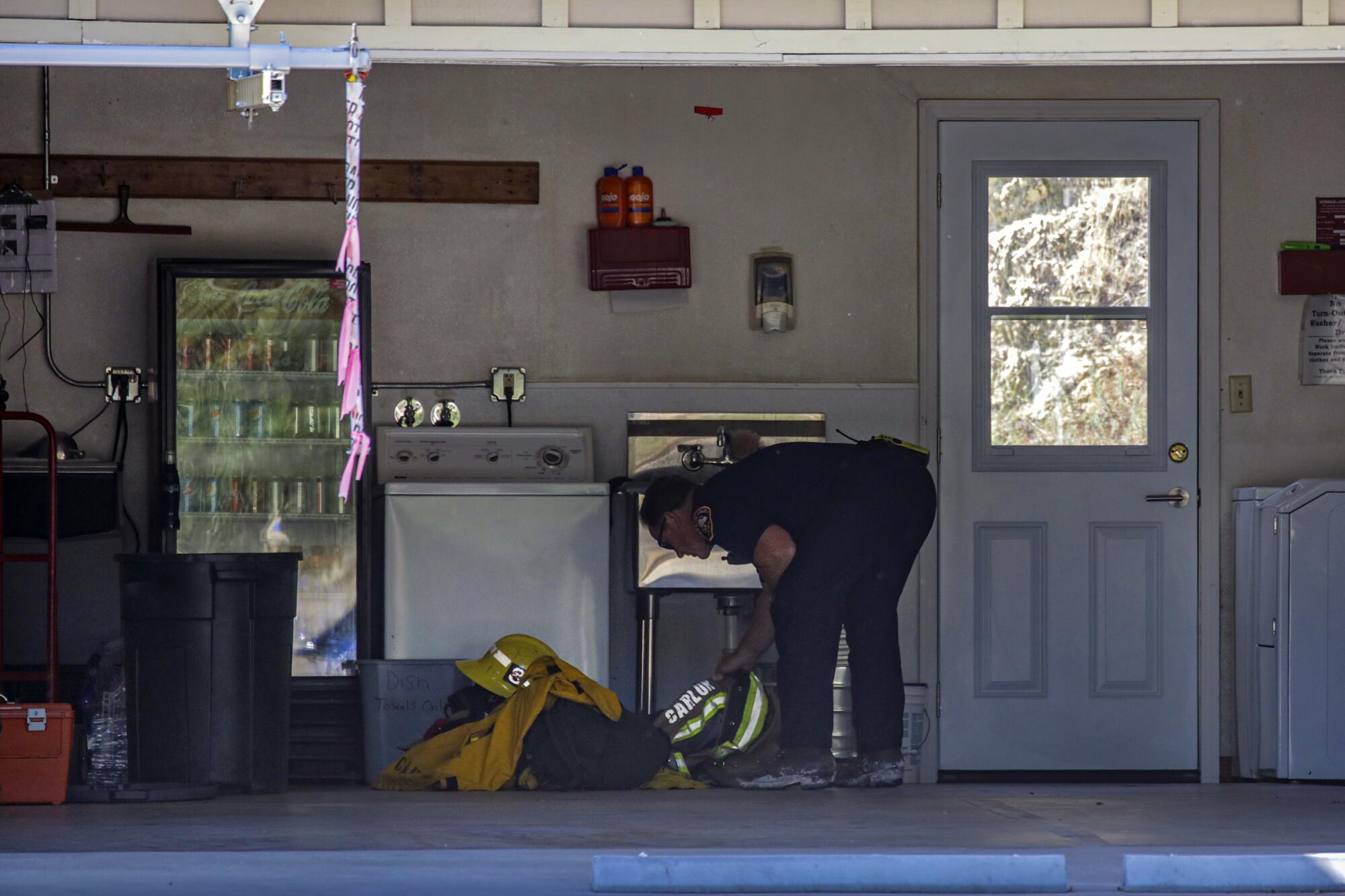 A Los Angeles County fire official looks over firefighter Tory Carlon's gear at Station 81 in Agua Dulce