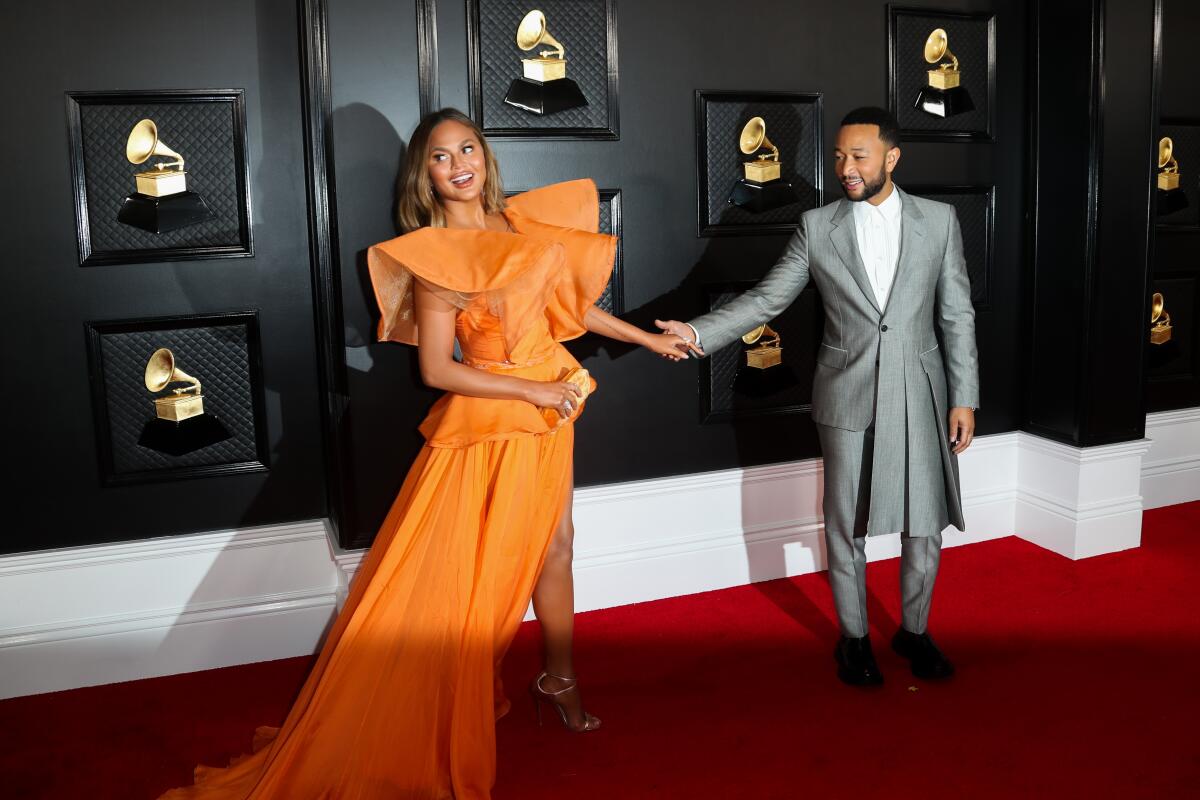 A woman in an orange dress and a man in a silver suit 