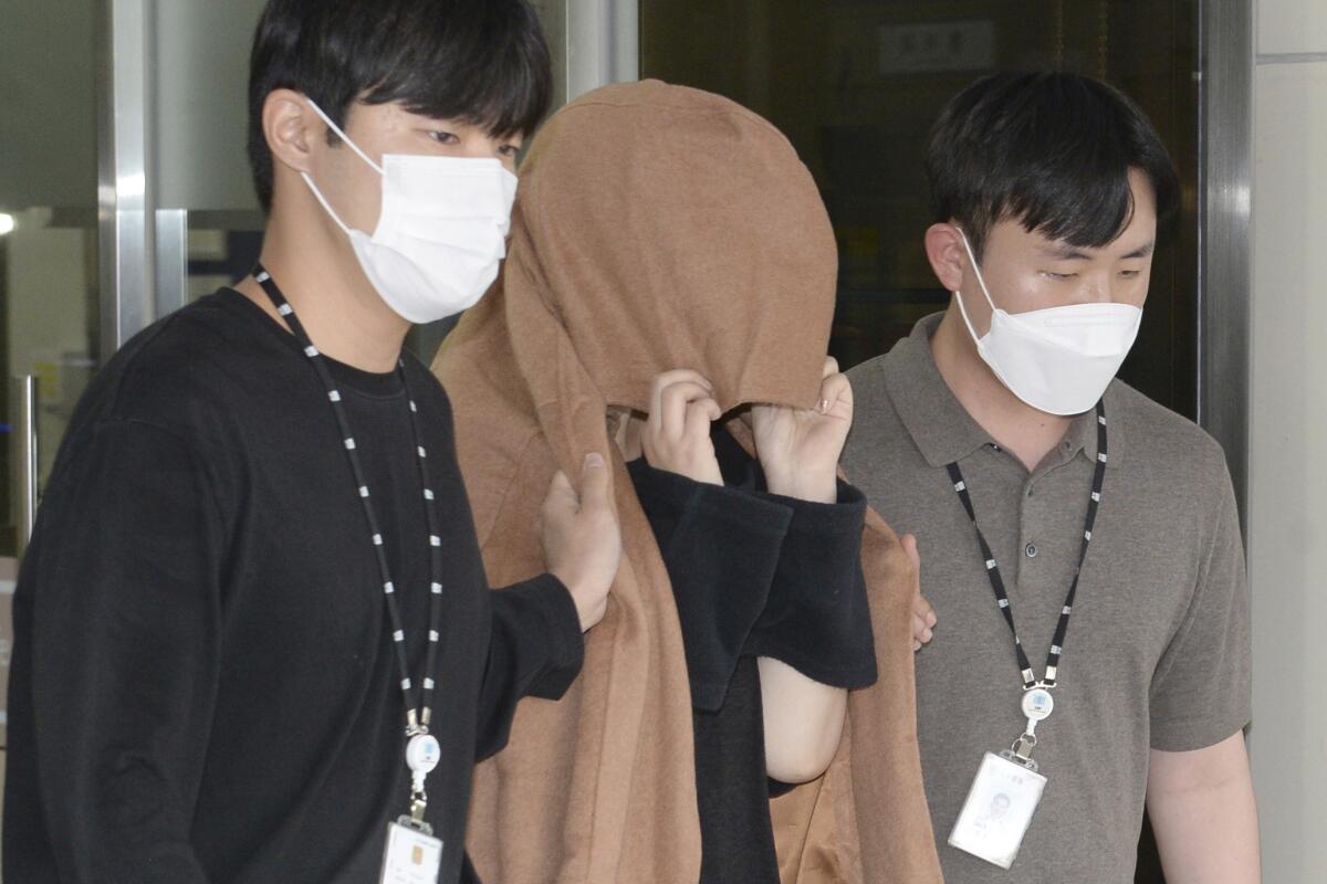 FILE - A woman, center, leaves to the Seoul Central District Prosecutors' Office at Ulsan Jungbu police station in Ulsan, South Korea, on Sept. 15, 2022. A South Korean court has approved the extradition of the 42-year-old woman facing murder charges in New Zealand over her possible connection to the bodies of two long-dead children found abandoned in suitcases in August. The Seoul High Court said Friday, Nov. 11, its decision came after the unidentified woman agreed to be sent back to New Zealand. (Bae Byung-soo/Newsis via AP, File)