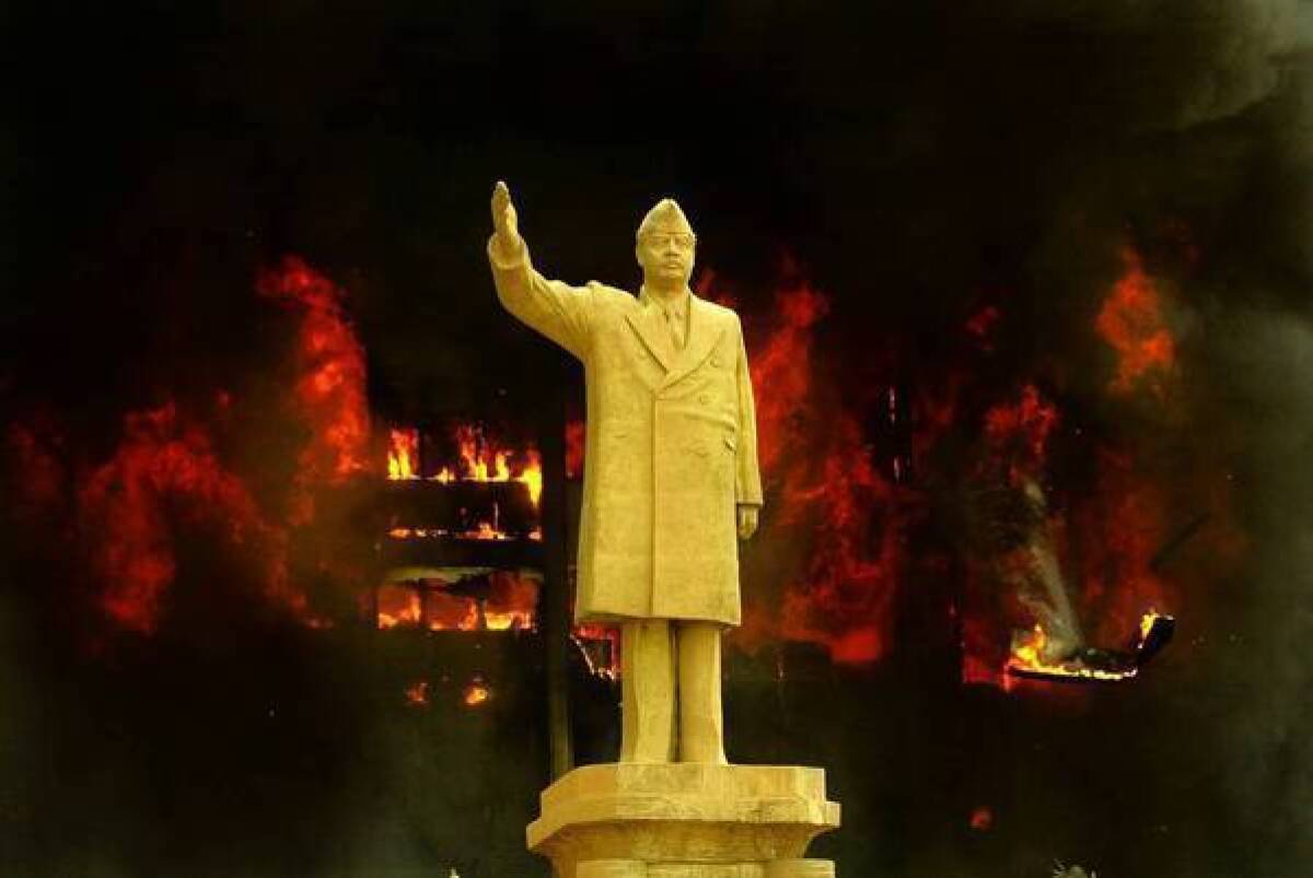 The Iraqi National Olympic Committee building, behind a statue of Saddam Hussein, goes up in flames in April 2003 as looters attack government structures in Baghdad.
