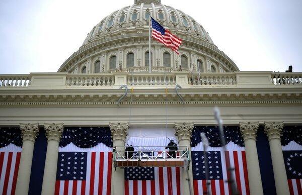 Two workers adjust the U.S. flag on the Capitol as preparations continue for President Obama's second inauguration ceremonies.