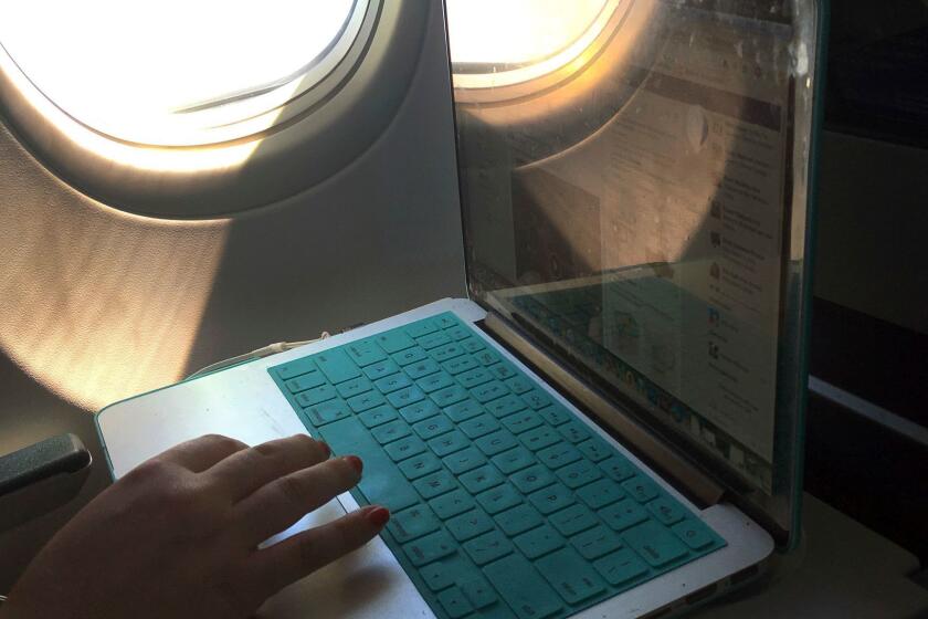 In this July 1, 2017, photo, a passenger uses a laptop aboard a commercial airline flight from Boston to Atlanta. (AP Photo/Bill Sikes)