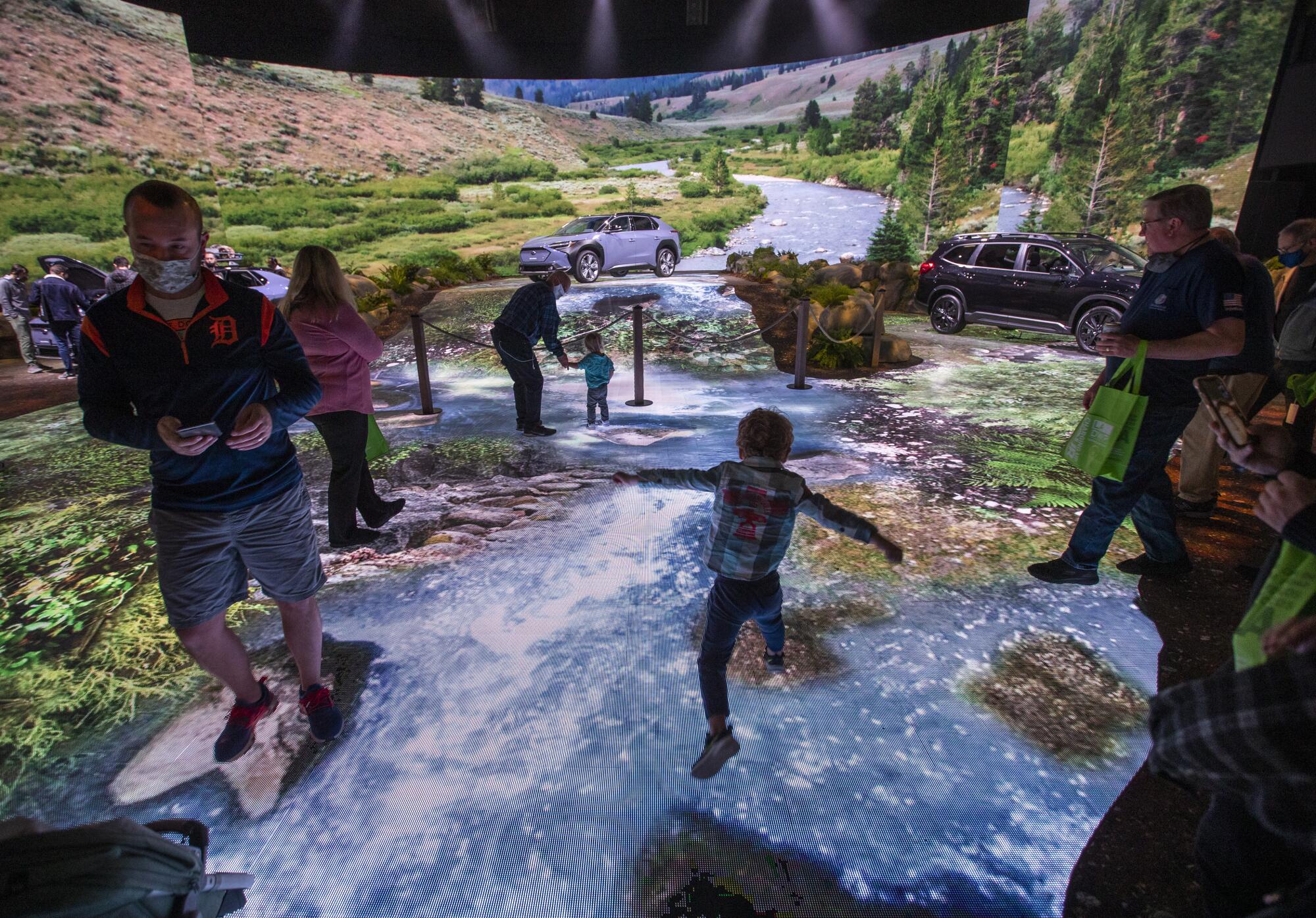 A child jumps from rock to rock over a virtual river at the Subaru display