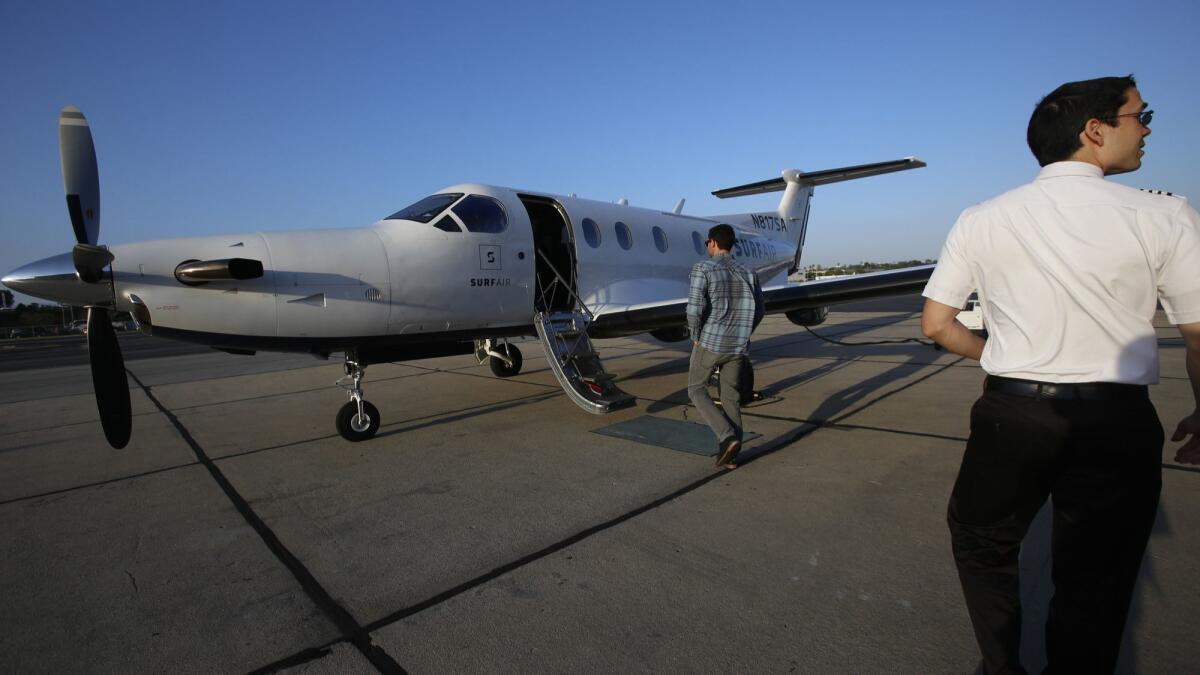 Capt. Chris Pimentel, right, waits for passengers to board a Surf Air commuter plane at Hawthorne Municipal Airport in 2015. Surf Air, an all-you-can-fly membership airline, is in a feud with the company that operated its planes in California since 2017.