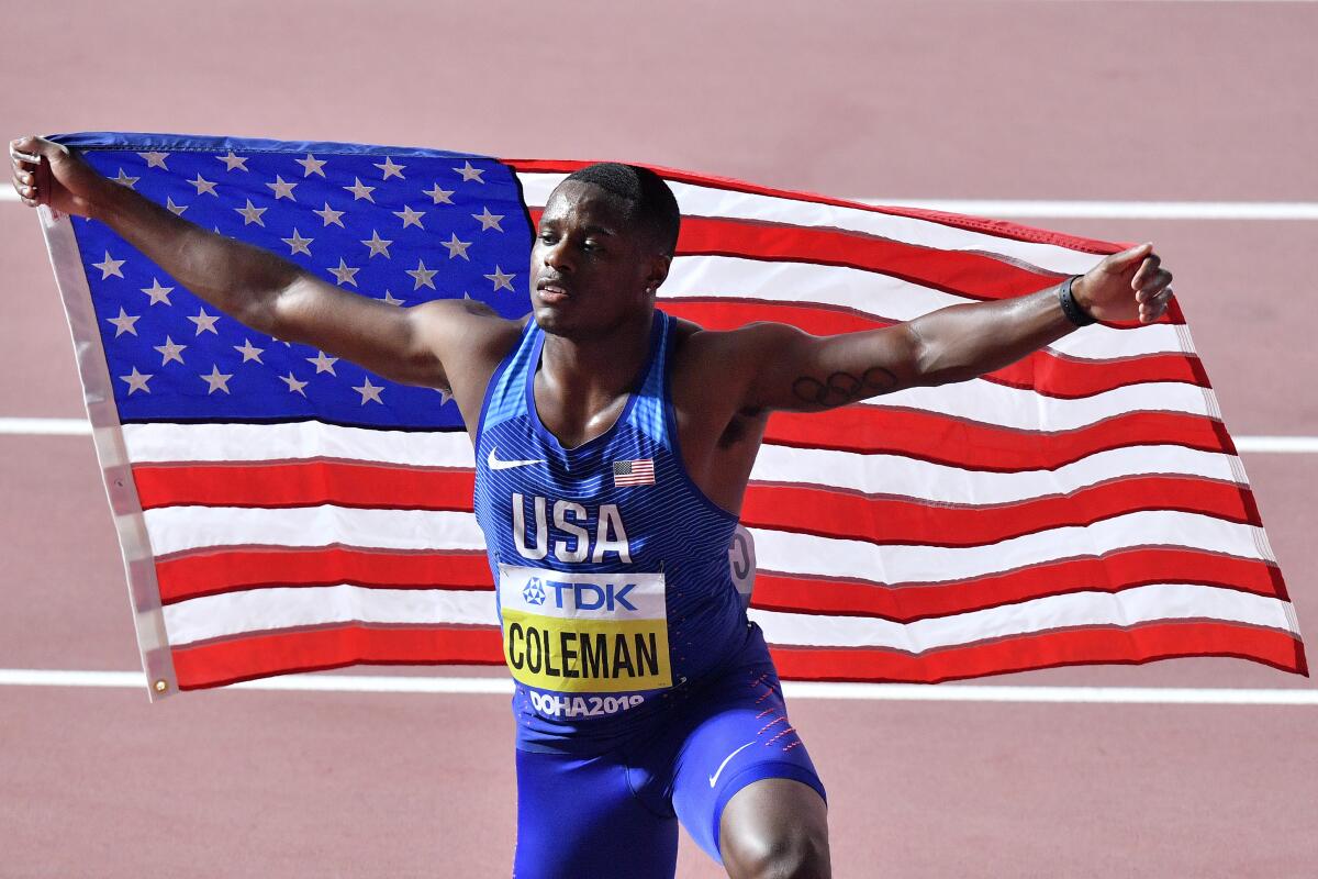 Christian Coleman poses with a U.S. flag after winning the 100-meter race at the 2019 world championships in Doha, Qatar. 