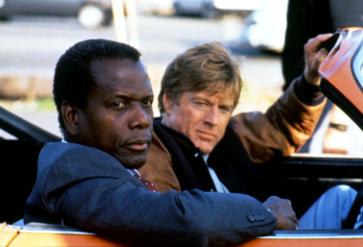 Two men sit in a convertible.
