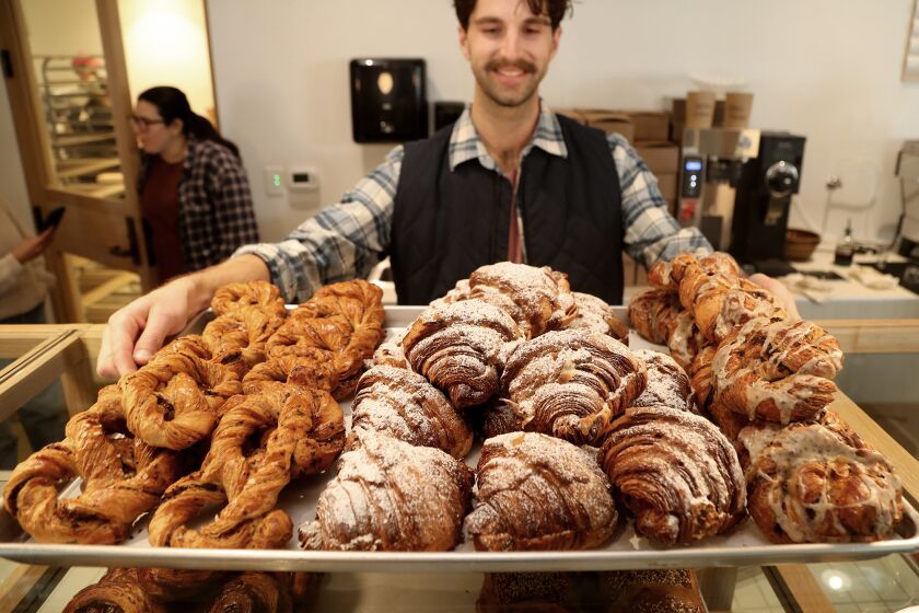 Riley Johnson pulls out a tray of various croissants made on Thursday at the newly opened Rye Goods in Tustin. (Kevin Chang / TimesOC)