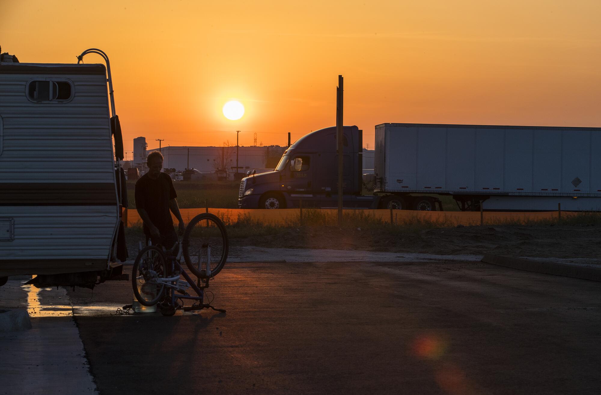 The sun sets behind Fontana traffic. Trucks proliferate to service the many warehouses.