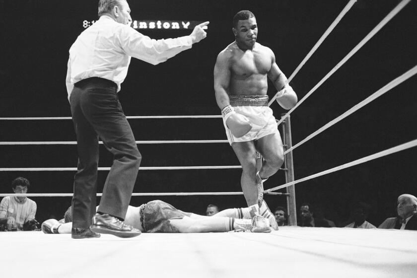 Ref Arthur Mercante points the way to the corner for Mike Tyson, right, after he knocked down Steve Zouski in the third round