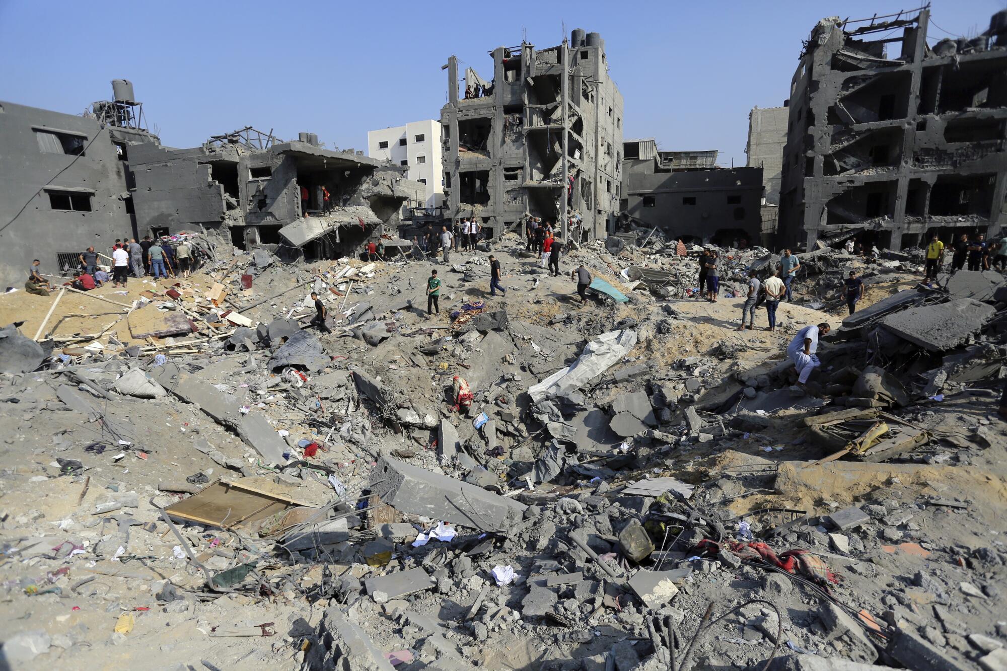 People wander amid debris of buildings leveled by Israeli airstrikes in Gaza
