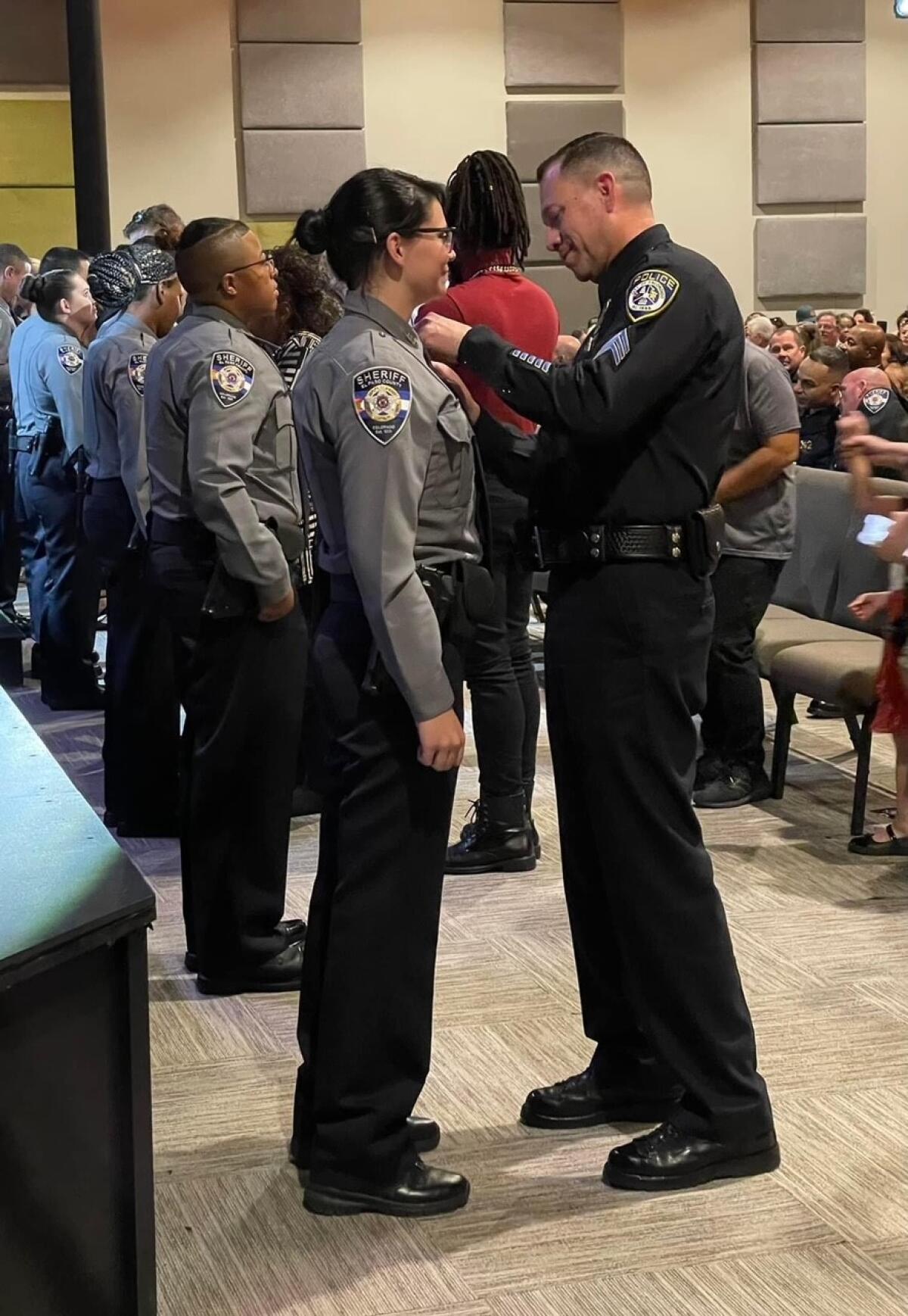 Escondido Police Sgt. Jeff Valdivia pins a badge on El Paso County Sheriff's Deputy Natalie Young.