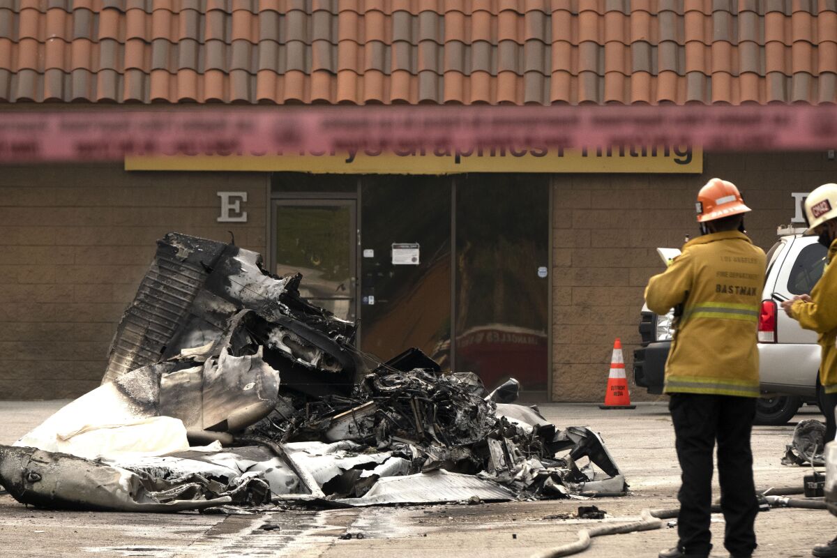 Firefighters look over what's left of a mangled plane that crashed in the Van Nuys area of Los Angeles on Friday.
