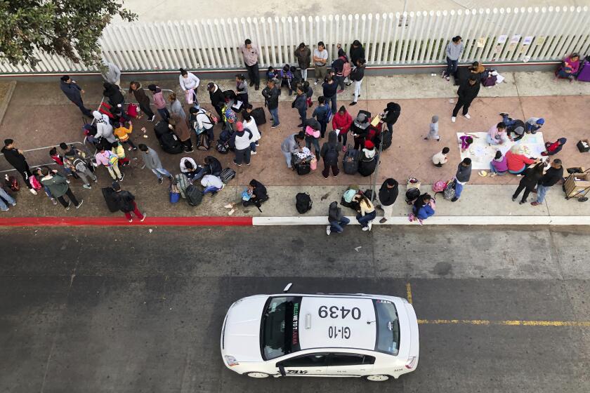 In this Nov. 10, 2019, photo, migrants gather at the U.S.-Mexico border in Tijuana, Mexico, to hear names called from a waiting list to claim asylum in the U.S. The U.S. has sent a Honduran migrant back to Guatemala in a move that marked a new phase of President Donald Trump’s immigration crackdown. (AP Photo/Elliot Spagat)