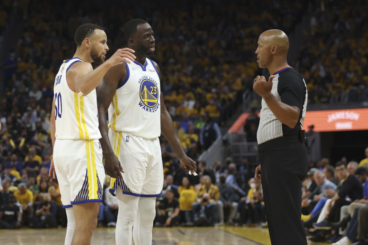 Golden State Warriors guard Stephen Curry, left, and forward Draymond Green (23) talk with referee Marc Davis during the second half of Game 1 of basketball's NBA Finals against the Boston Celtics in San Francisco, Thursday, June 2, 2022. (AP Photo/Jed Jacobsohn)