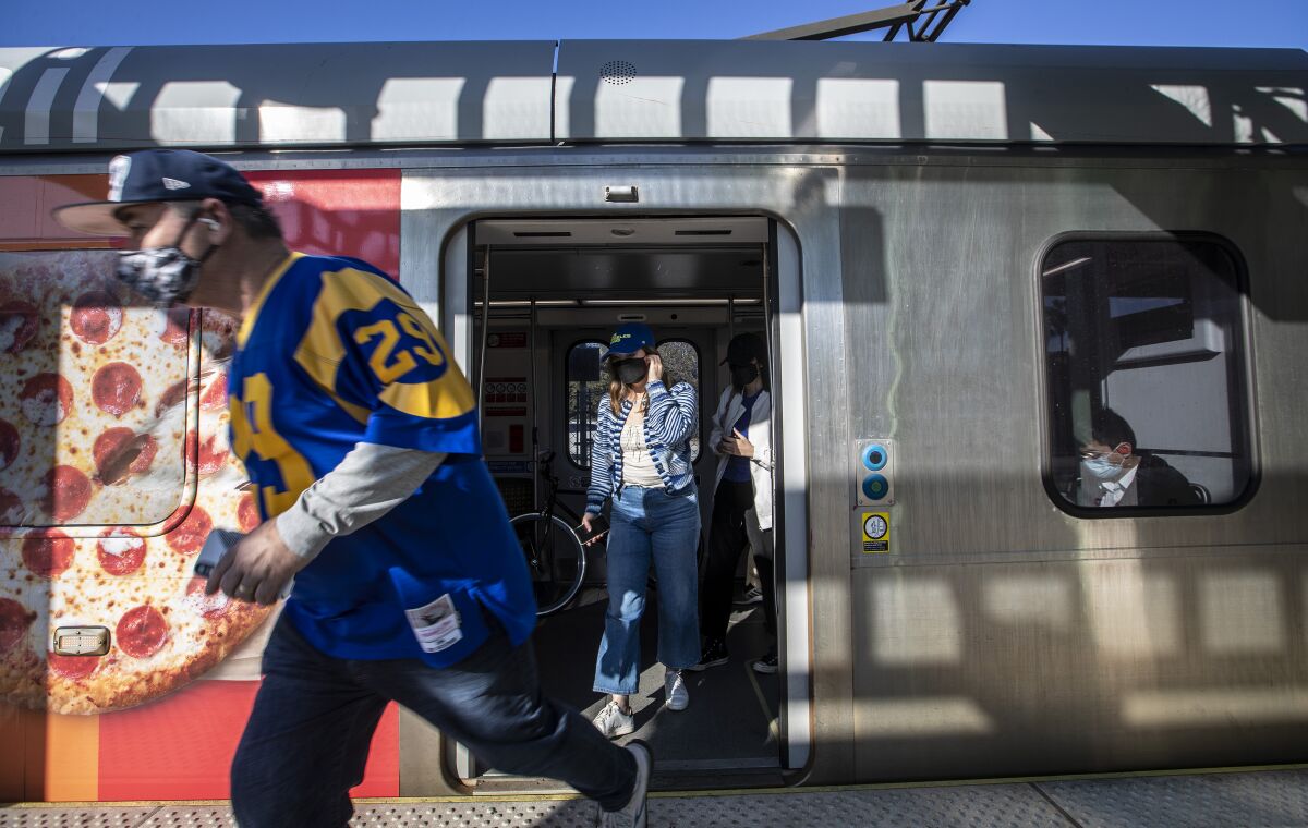 A fan runs to board a bus from a Metro stop to SoFi Stadium for a Rams game.