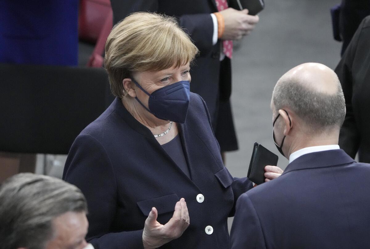 Former Chancellor Angela Merkel talks to Chancellor Olaf Scholz during the German Federal Assembly.