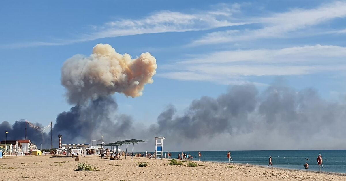 Billowing smoke serves as a backdrop for beachgoers 