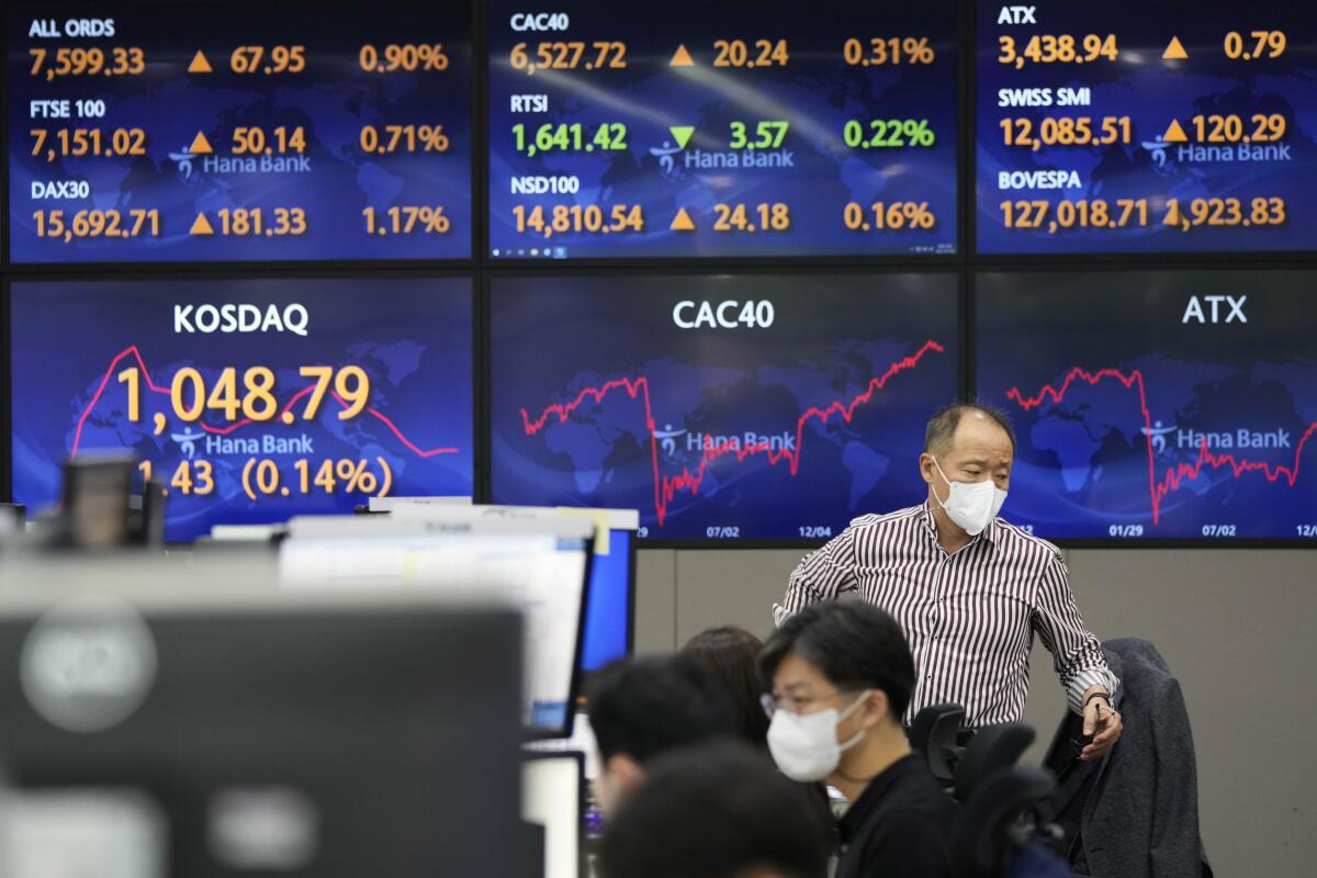 A currency trader passes by screens showing foreign exchange rates at the foreign exchange dealing room of the KEB Hana Bank headquarters in Seoul, South Korea, Thursday, July 8, 2021. Asian stock markets fell Thursday after the Federal Reserve discussed a possible reduction in U.S. economic stimulus and Japanese officials prepared to declare a coronavirus state of emergency during the Olympics due to a surge in infections. (AP Photo/Ahn Young-joon)