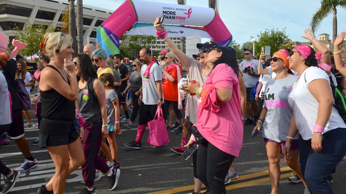 Walkers take selfies at the start of the Susan G. Komen Orange County More Than Pink Walk in 2019.