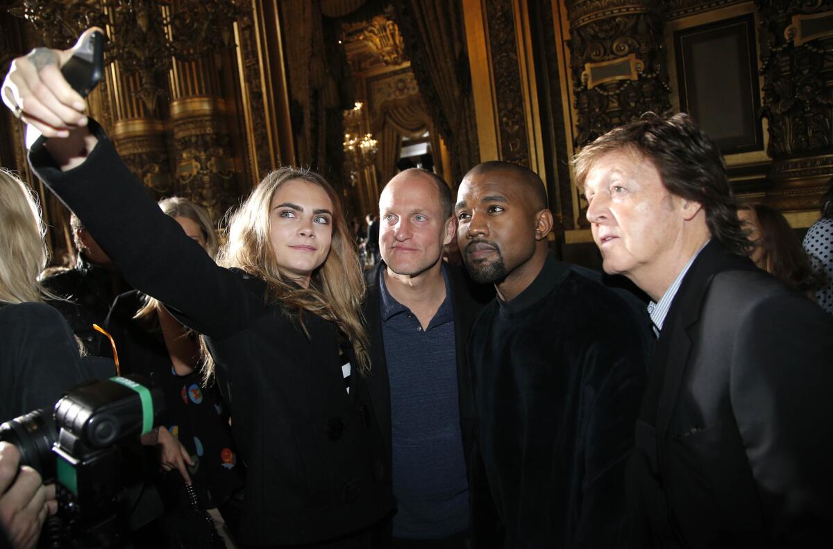 Model Cara Delevingne takes a selfie with Woody Harrelson, Kanye West and Paul McCartney before Stella McCartney's show Monday at Paris Fashion Week.