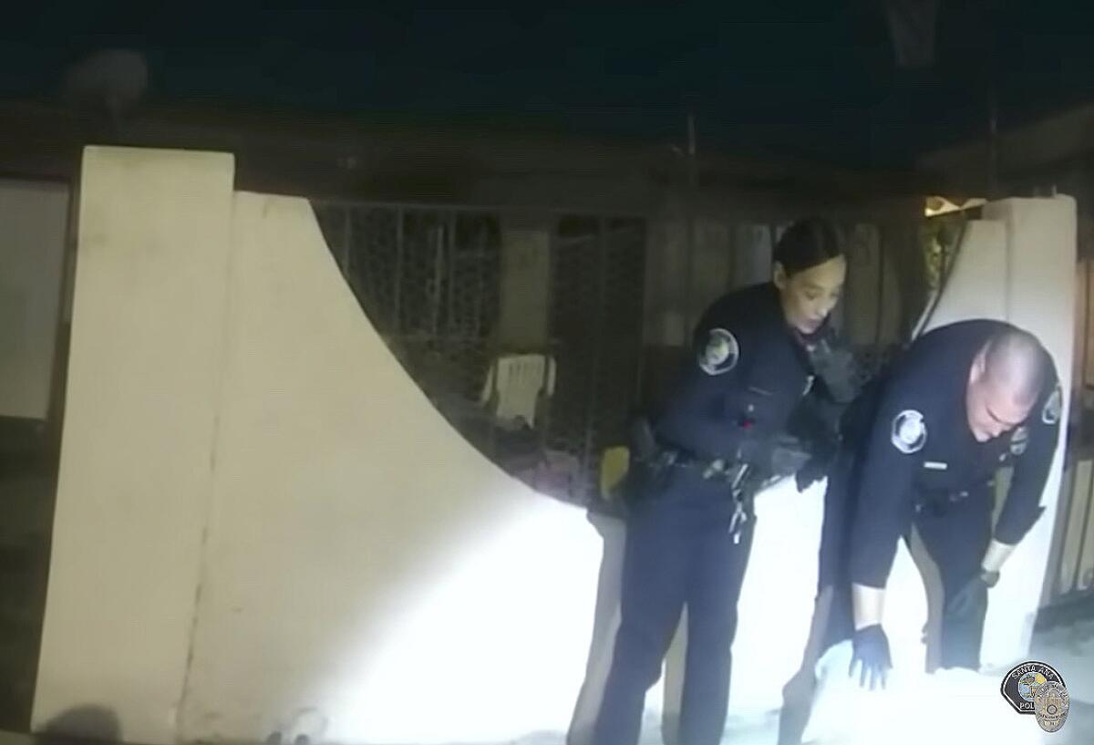 Two officers bending over a man lying on the ground, seen in police body camera footage