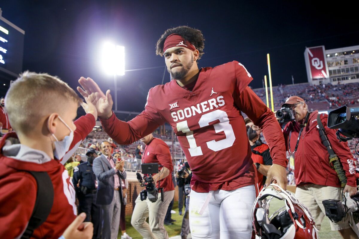 FILE - Oklahoma quarterback Caleb Williams (13) celebrates with fans while walking off the field after the team's team's 52-31 win over TCU in an NCAA college football game Saturday, Oct. 16, 2021, in Norman, Okla. Caleb Williams is transferring to Southern California, following his former coach Lincoln Riley from Oklahoma to the Trojans. Williams posted his long-awaited announcement on social media Tuesday, Feb. 1, 2022, a video that included the former five-star recruit in a USC uniform and famous Trojans fan Snoop Dogg rapping. (Ian Maule/Tulsa World via AP, File)