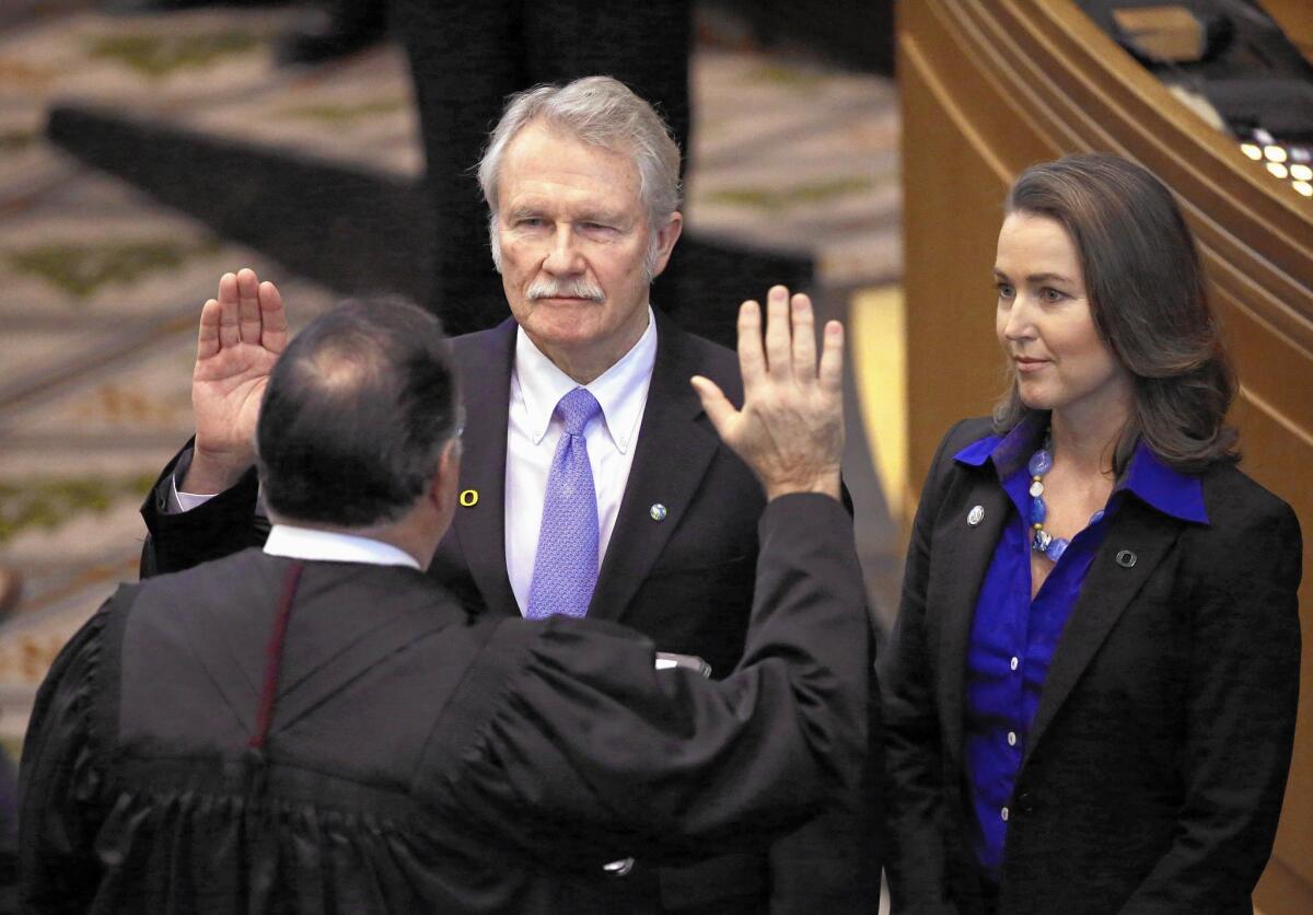 Oregon Gov. John Kitzhaber is sworn in Jan. 12 with First Lady Cylvia Hayes at his side. Friday, he announced he would step down amid allegations that Hayes sought to improperly influence him.