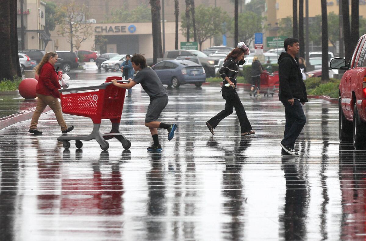 Shoppers going in and out of the Target store on Harbor Boulevard in Costa Mesa run for cover as rain begins to fall Wednesday.