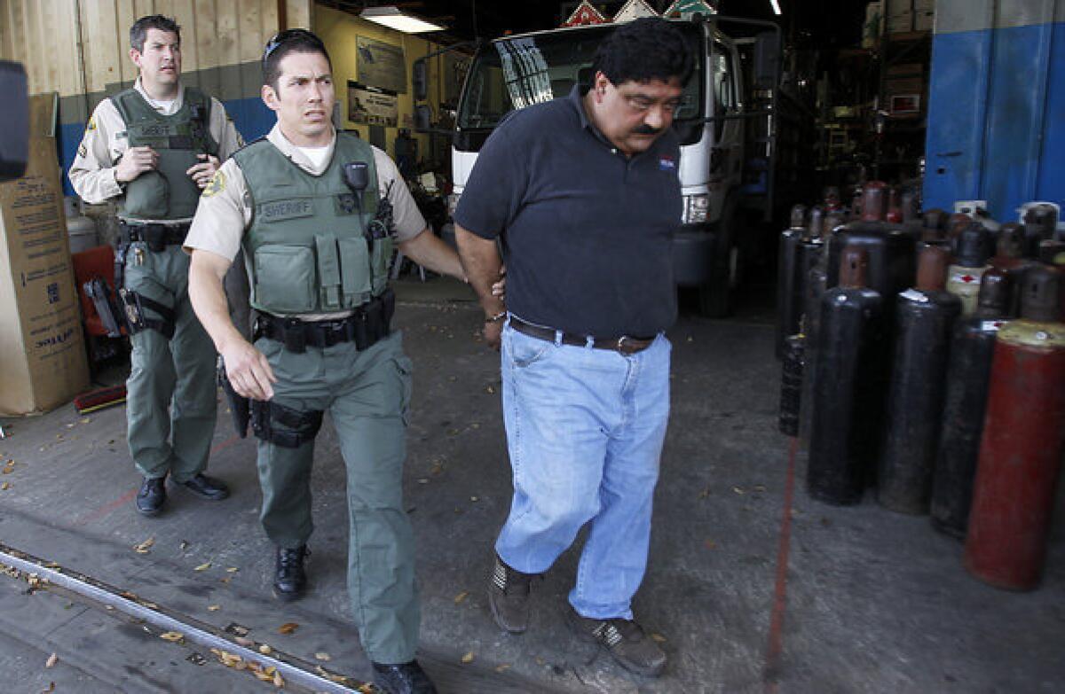 L.A. County sheriff's deputies escort a suspect after a raid on Victory Welding & Supply in South Los Angeles on Friday.