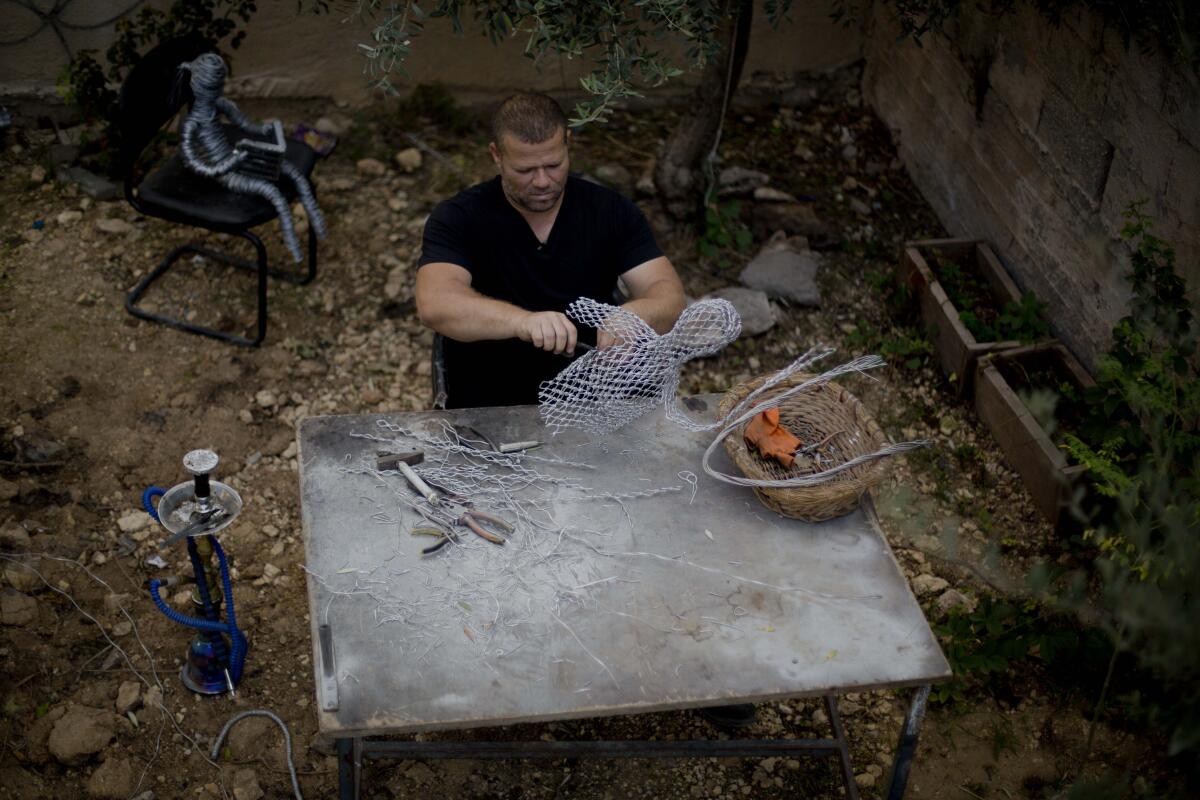 Palestinian artist Haitham Khateeb uses old metal wire to make art objects reflecting scenes of Palestinian daily life in the garden of his house in the West Bank village of Bilin.