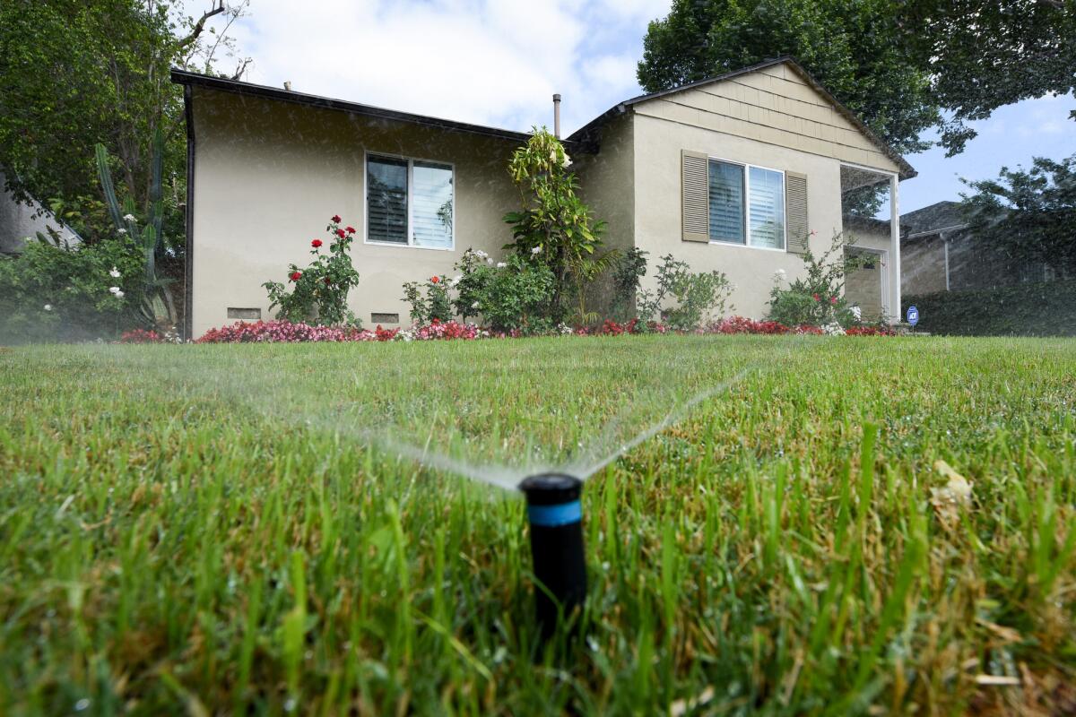 Sprinklers water the front lawn of a house on Zelzah Avenue in Encino earlier this year.