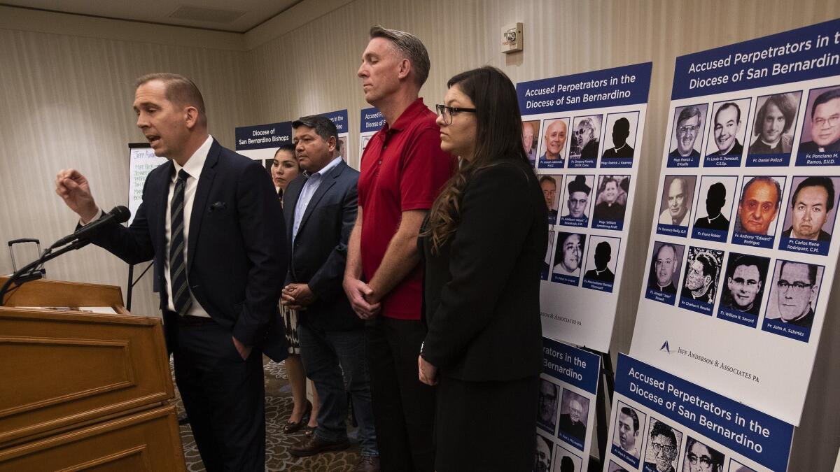 Attorney Mike Reck, left, talks to the media about the release of a report on clergy sex abuse, disclosing the identities and histories of 84 accused offenders who worked in the Diocese of San Bernardino.