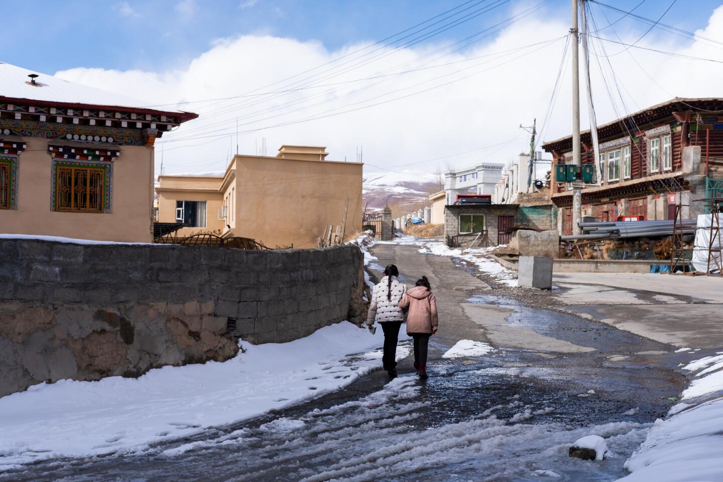 Two women walk up a snowy road in Garze on Feb. 9, 2020.