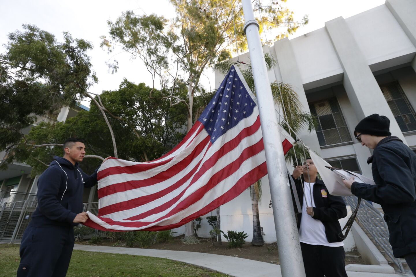 Sunny Vargas, 16, left, Carlos Bello, 16, and Natalie Matossian, 14, raise flags outside Franklin High School as Los Angeles schools reopened on Wednesday.