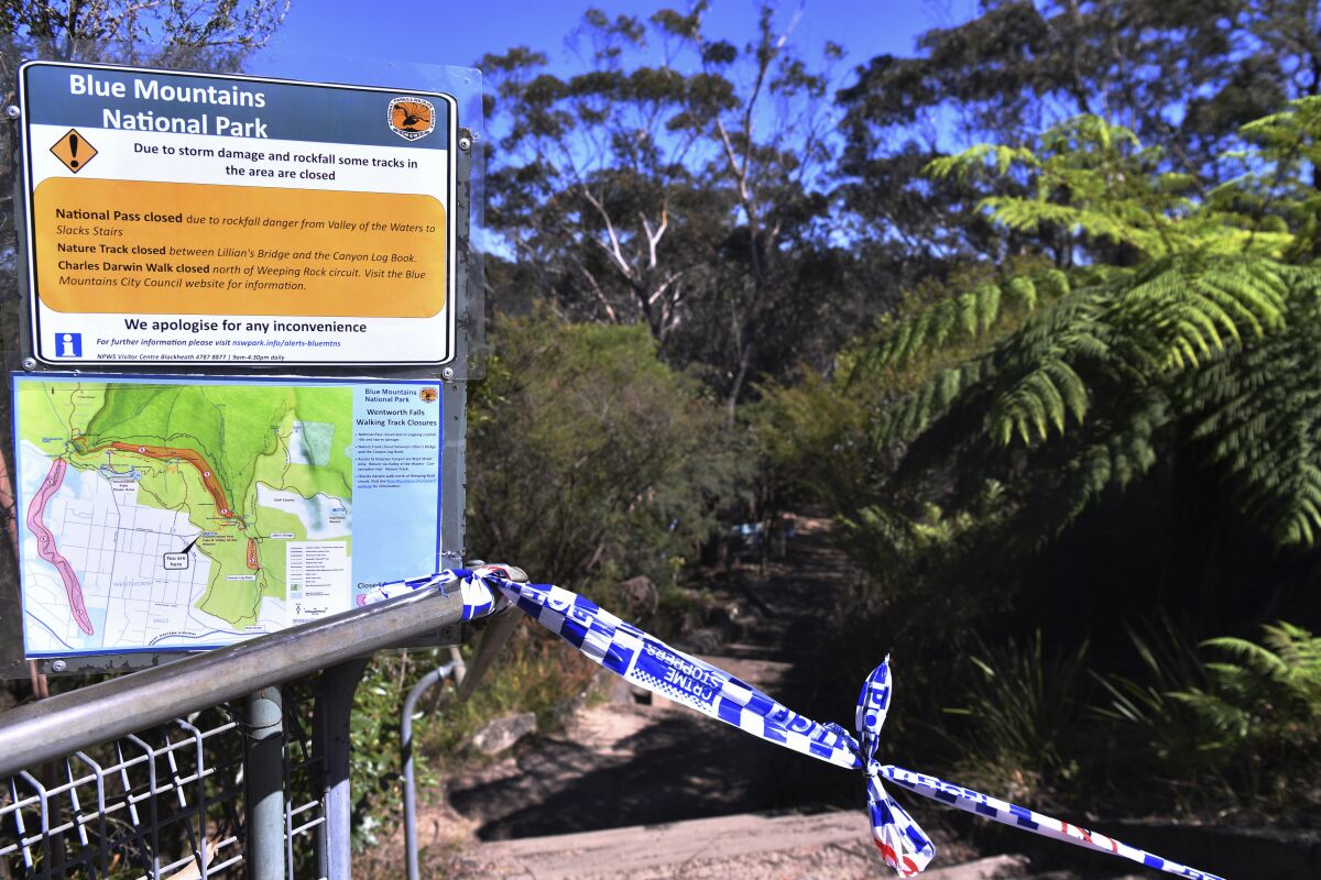 The entrance to the walking track where a landslide killed 2 and injured two others is tapped off at Wentworth Falls in the Blue Mountains, west of Sydney, Tuesday, April 5, 2022. A British family of five was caught in a landslide while walking in Australia's Blue Mountains, and the father and 9-year-old son died. (Dean Lewins/AAP Image via AP)