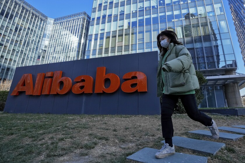 A woman wearing a face mask run past the offices of Chinese e-commerce firm Alibaba in Beijing, Monday, Dec. 13, 2021. An employee of Chinese e-commerce giant Alibaba who was fired after she went public with a sexual assault allegation told a local newspaper that published Saturday, Dec. 11, 2021, that she is not encouraging other victims in China to come forward because doing so “will only cause them to suffer more hurt.” (AP Photo/Andy Wong)