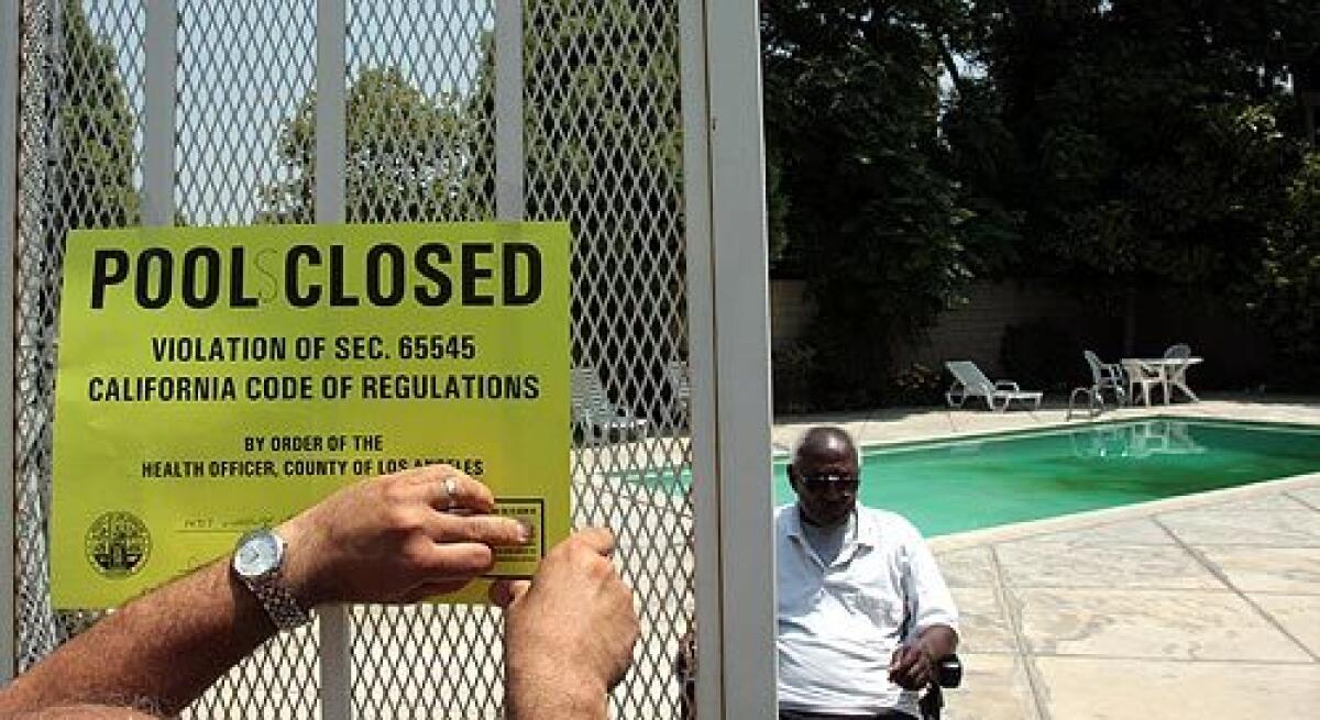 L.A. County inspector Sarkis Kharadjian closes an apartment complex's pool and spa in Panorama City as building manager Sylvester Norwood watches. More photos >>>