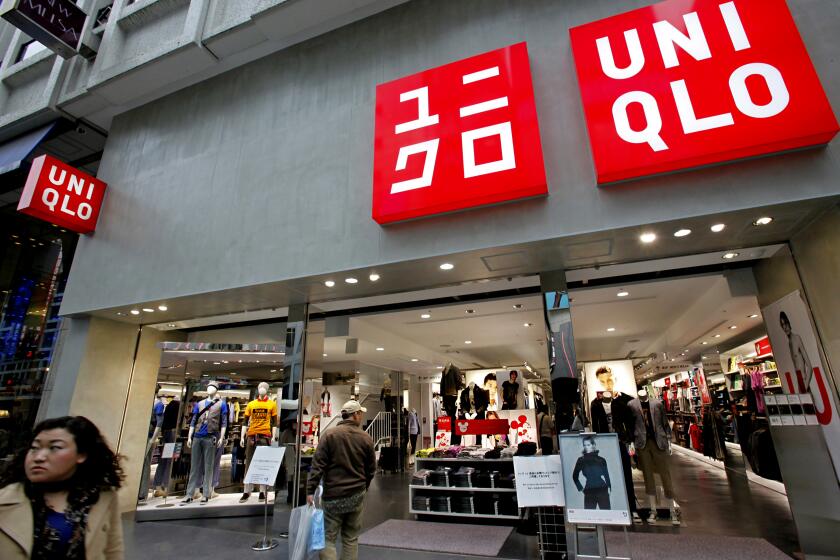 FILE - In this April 7, 2010 photo, a passerby looks at a Uniqlo shop in Tokyo. Japanese fashion giant Fast Retailing Co., which makes popular Uniqlo brand clothing, is tightening controls on treatment of workers at key suppliers’ factories in China following complaints by labor rights groups. Members of two labor rights groups said Friday, Jan. 16, 2015 they are planning meetings next week with representatives of the company. (AP Photo/Shizuo Kambayashi, File)