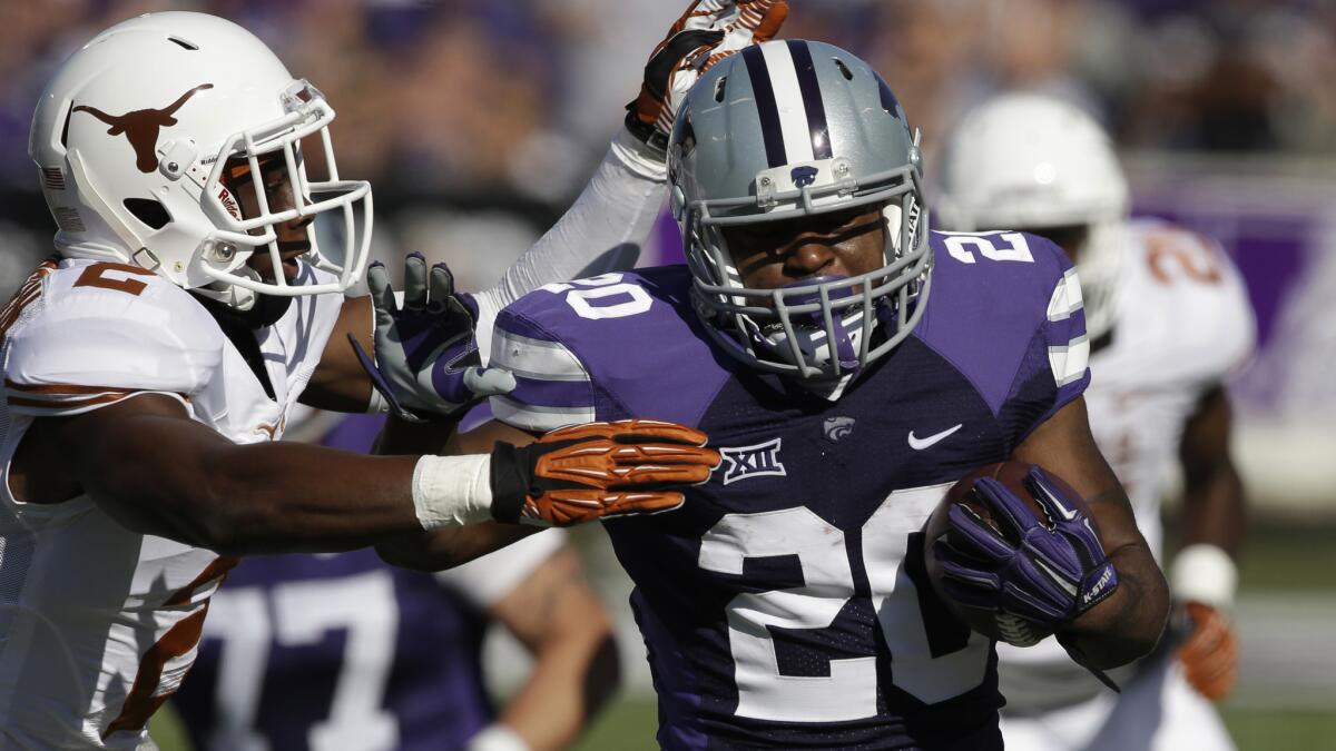 Kansas State running back DeMarcus Robinson, right, tries to fend off Texas safety Mykkele Thompson during the first half of the Wildcats' win Saturday.