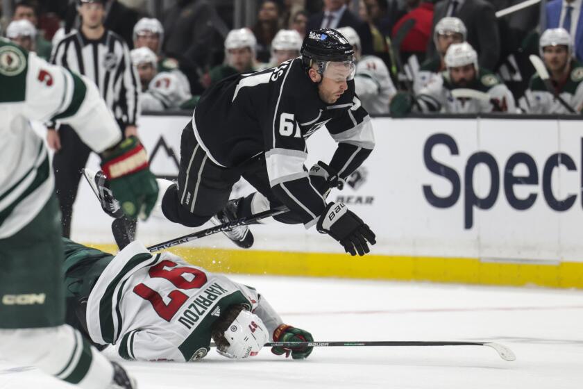 Los Angeles Kings center Trevor Lewis (61) trips over Minnesota Wild left wing Kirill Kaprizov (97) during the second period of an NHL hockey game Wednesday, March 20, 2024, in Los Angeles. (AP Photo/Yannick Peterhans)