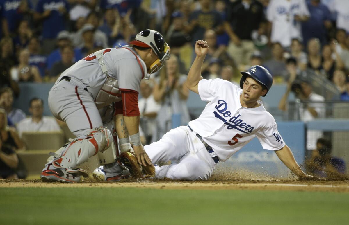 Dodgers shortstop Corey Seager (5) slides into home plate in front of Nationals catcher Wilson Ramos to score on a single.