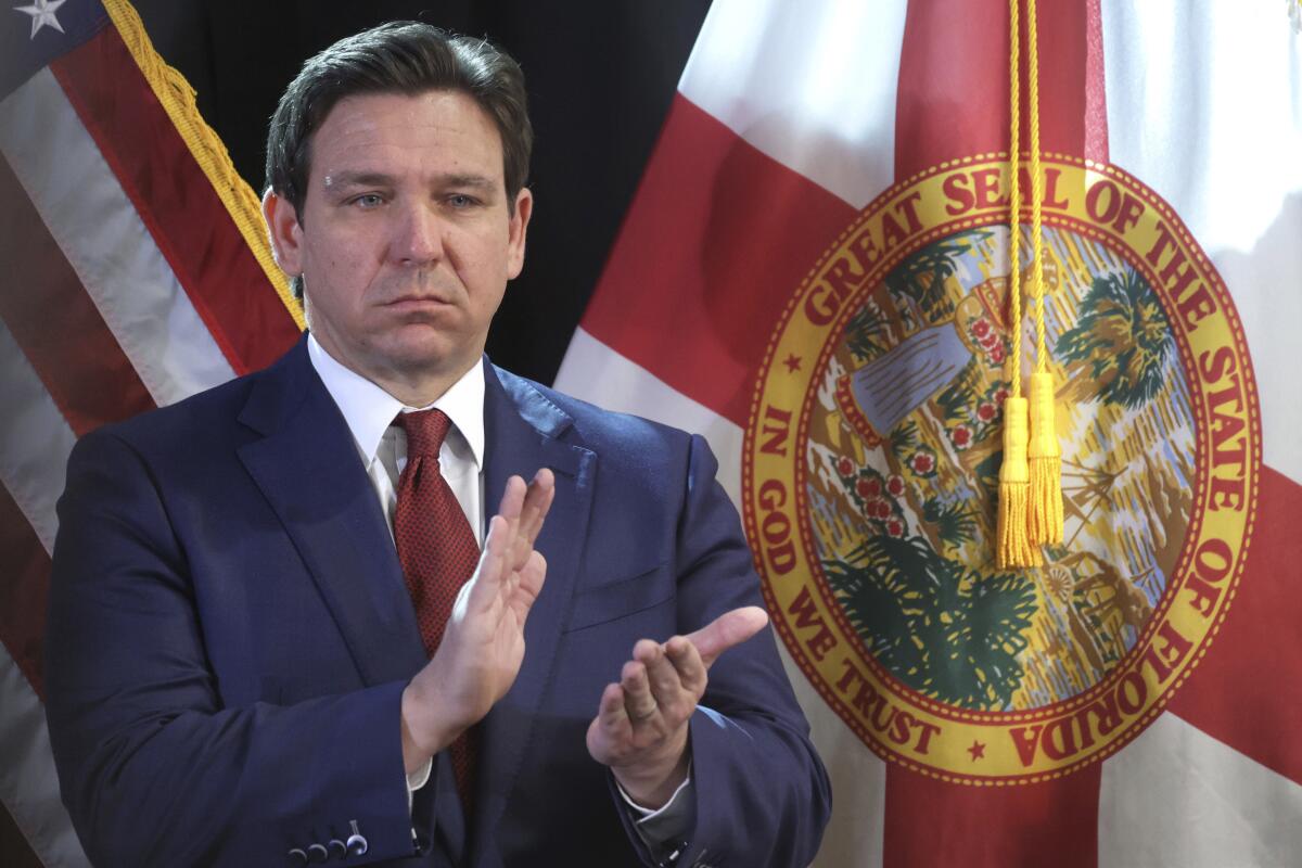 Florida Gov. Ron DeSantis applauds in front of U.S. and Florida flags