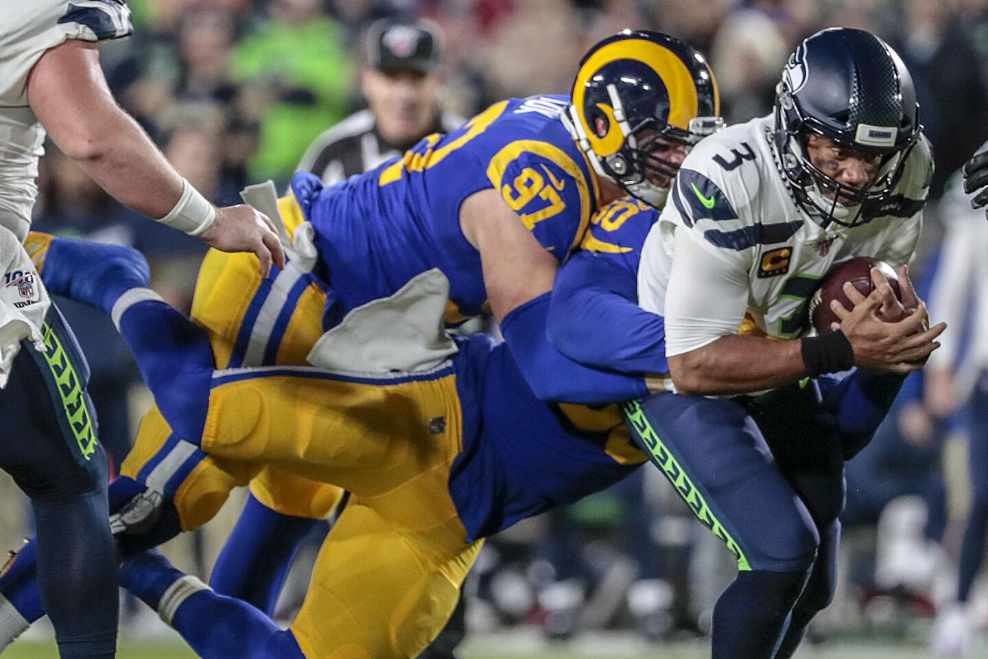 Seattle Seahawks quarterback Russell Wilson is sacked by Los Angeles Rams outside linebacker Samson Ebukam and defensive end Morgan Fox.